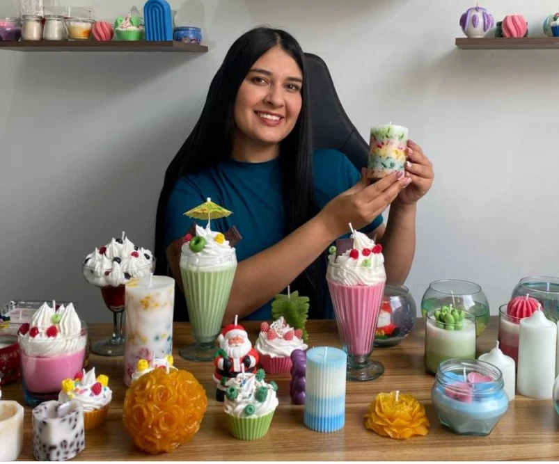 Foto de la creadora del curso Erika Barbosa con ejemplo de velas creadas por el curso